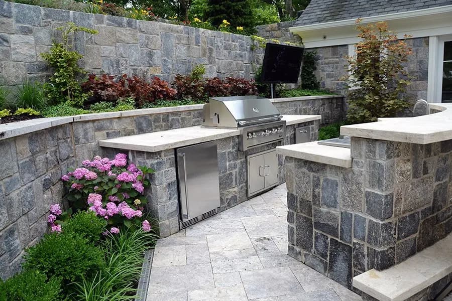 Stone outdoor kitchen with grill island and mounted TV