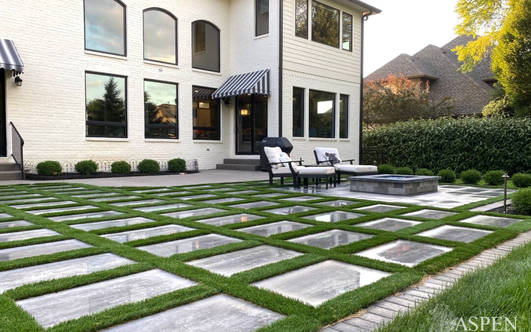 Checkerboard concrete-and-turf patio behind a two-story home