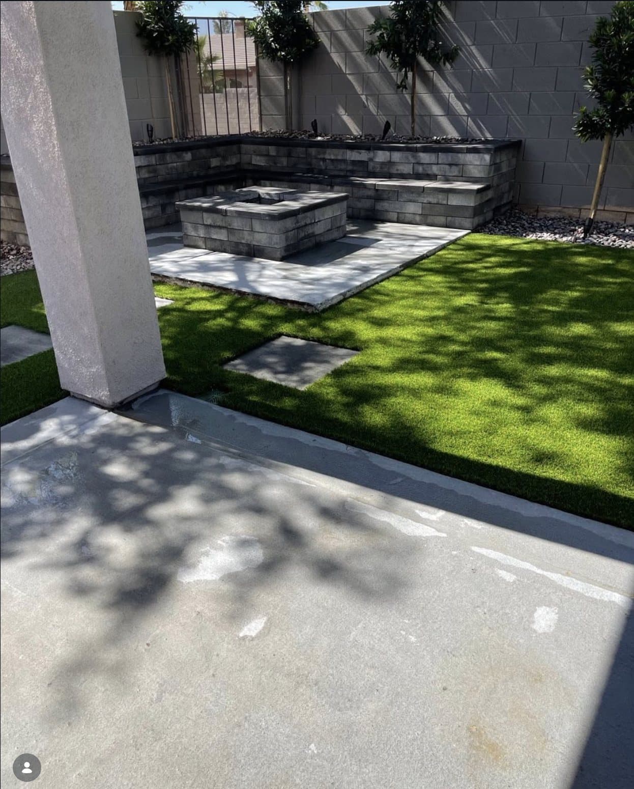 Backyard concrete patio with built-in fire pit and seat wall